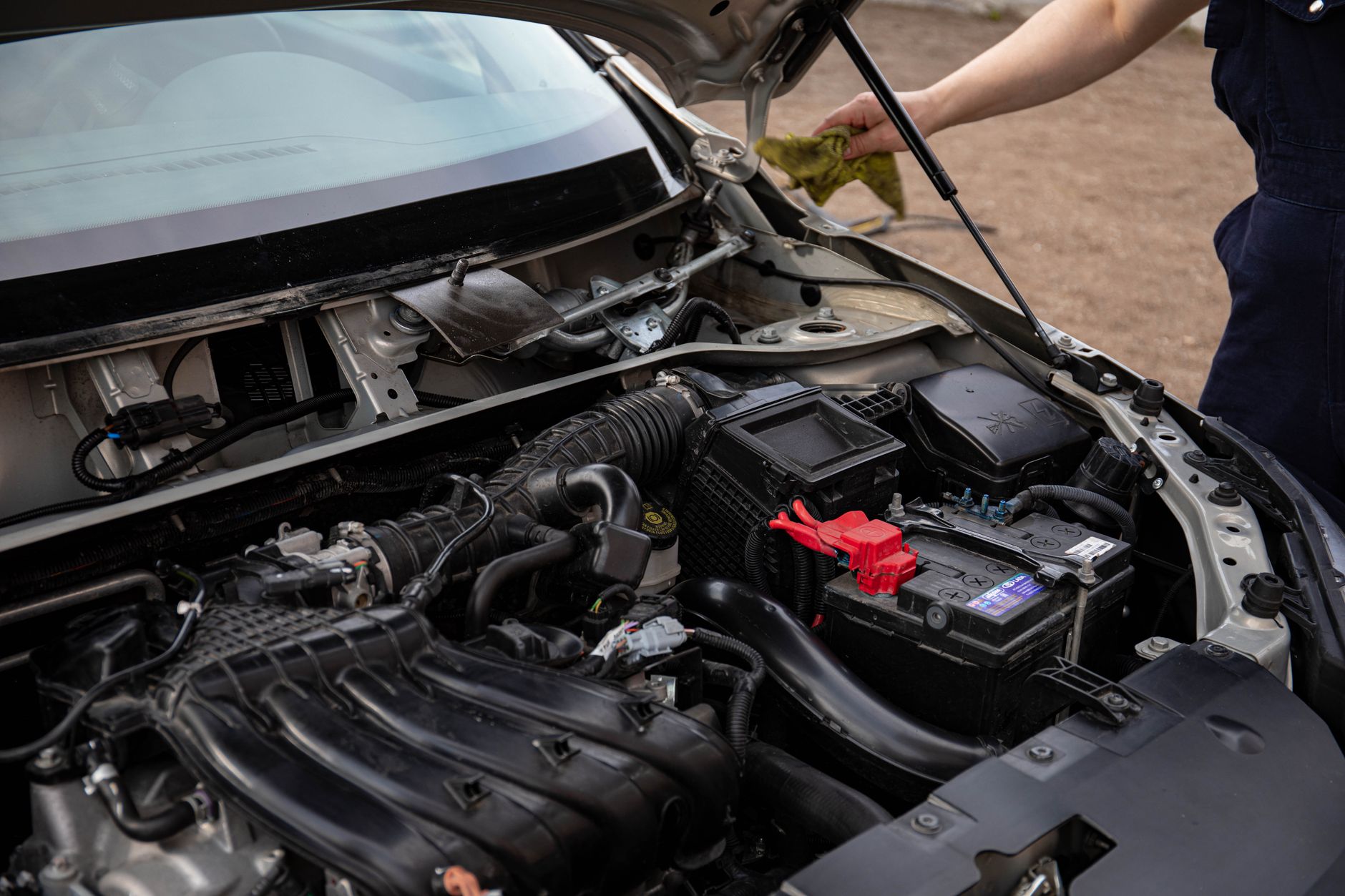 Mechanic inspecting car engine and battery
