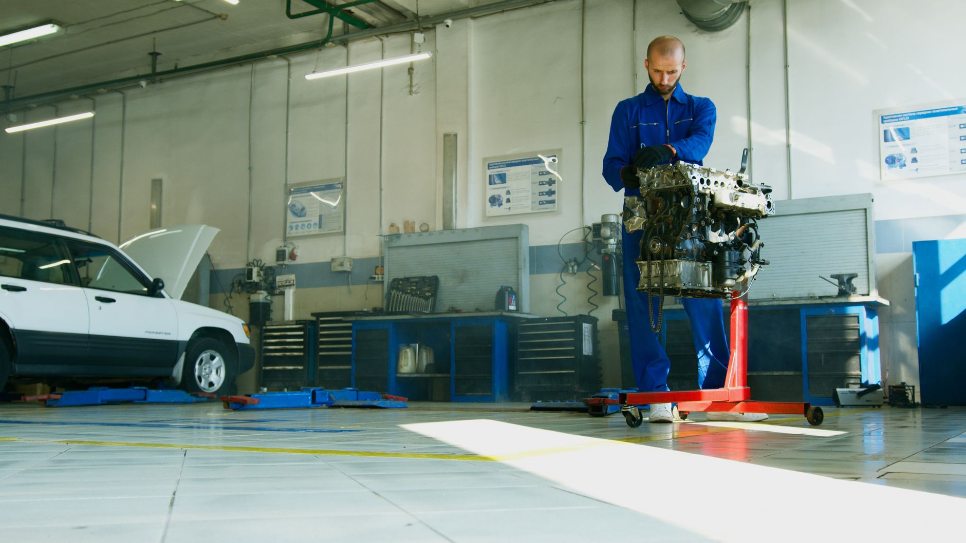 Mechanic lifting car engine in well-lit shop